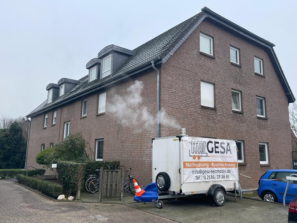 GESA service truck parked in front of a brick residential building with mansard roof and renovation equipment
